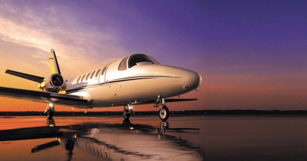 white and burgundy jet on the wet tarmac with a purple sky