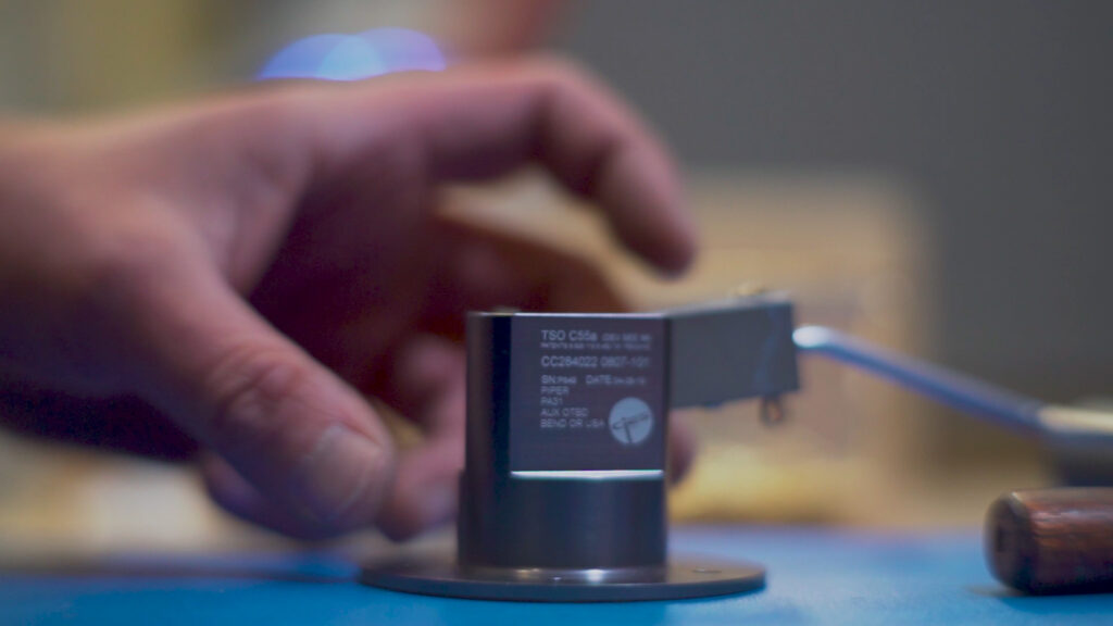 close-up of hard-anodized sender housing with a hand nearby